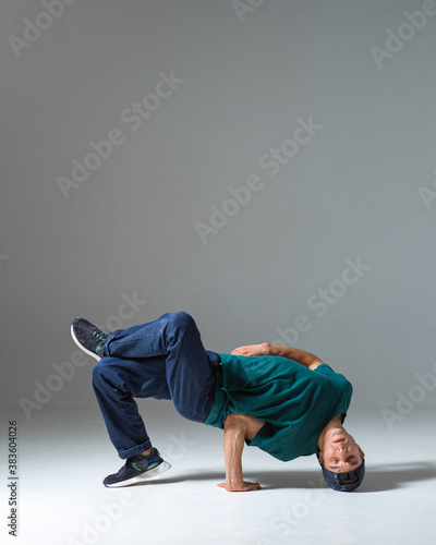 Young guy breakdancer dancing on the floor isolated on gray background. Breakdance lessons