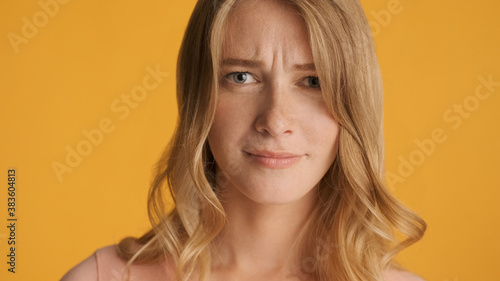 Portrait of young woman doubtfully looking in camera isolated on