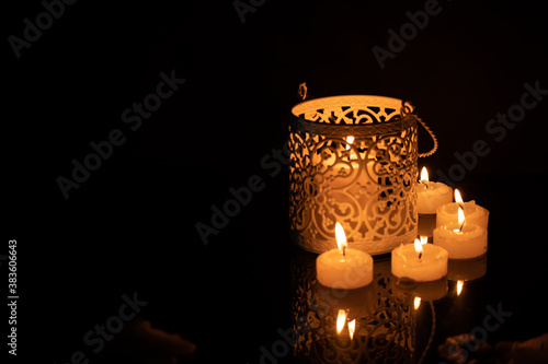 Intrincate metal candle holder with a lighting scented candle are displayed on the blak stone table in the dark living room of the house. Selective focus © HC FOTOSTUDIO