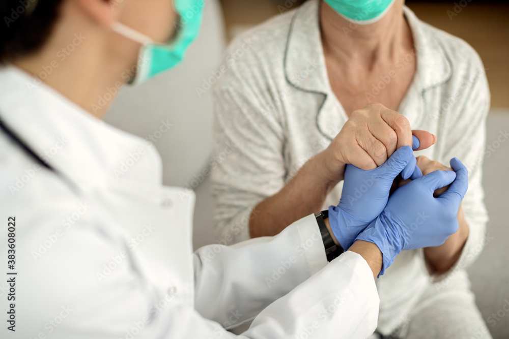Close-up of a doctor and senior woman holding hands during home visit. Close-up of a doctor and senior woman holding hands during home visit.