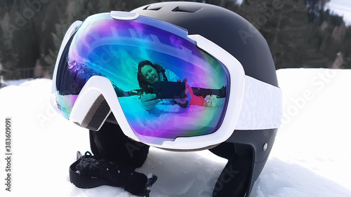 View of a ski helmet with sunglasses reflecting a woman. Landscape, industry, sports concept. photo