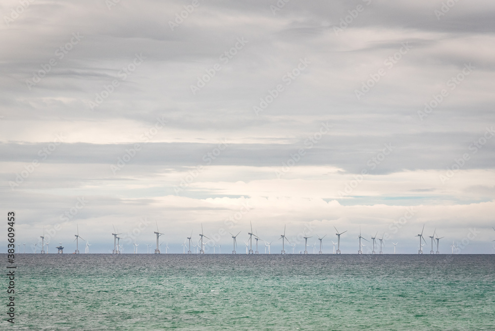 A wind farm off the coast of Cumbria in the UK. Wind turbines on the horizon in the middle of the ocean providing power for the national grid.