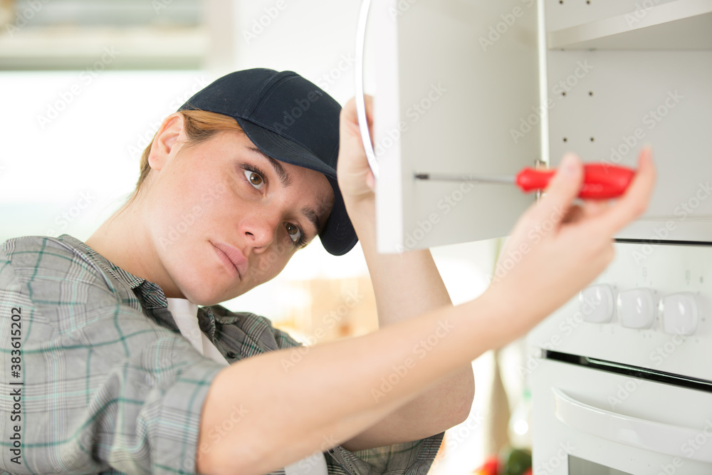 woman using a screw driver while installing a cabinet woman using a screw driver while installing a cabinet