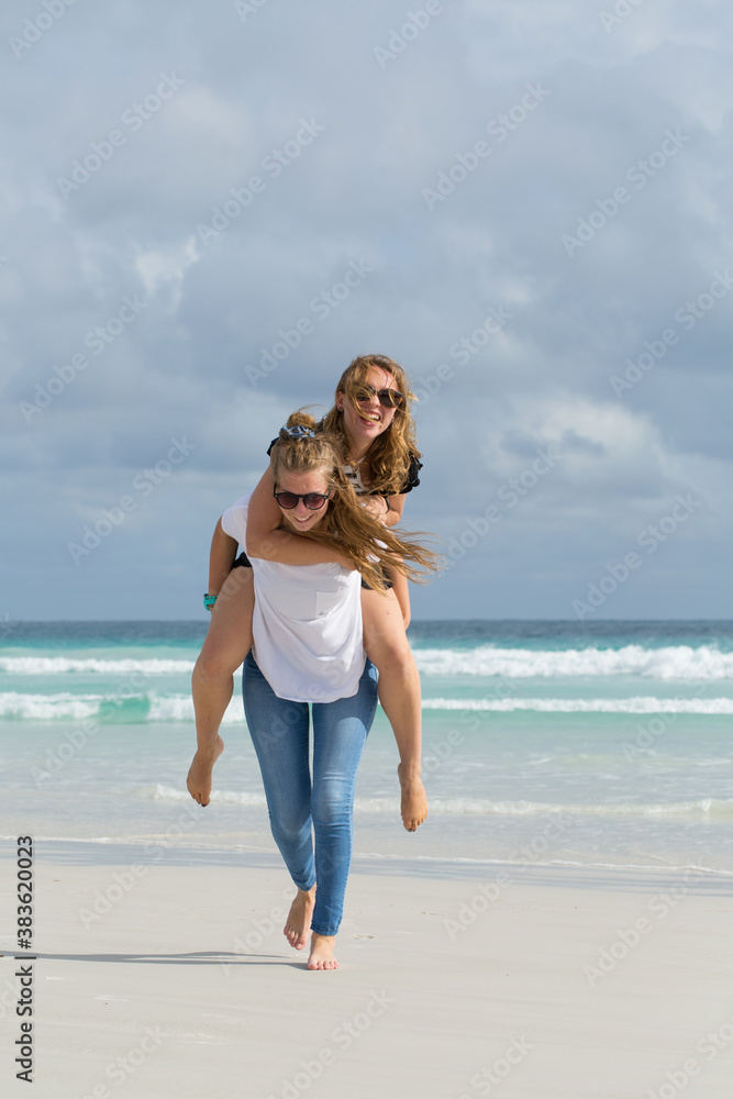 Teenage girls piggy backing on the beach Teenage girls piggy backing on the beach