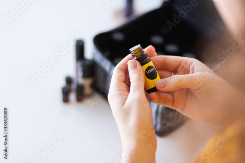 Person holding bottle of lemon essential oil in hands on white photo