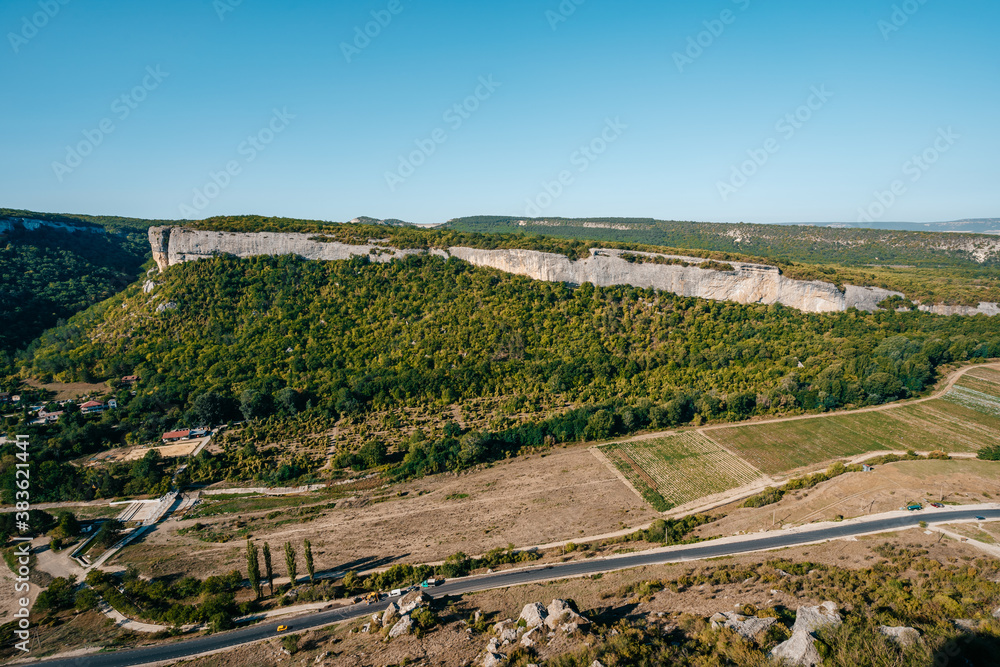 A rural road in the middle of rolling green valley photographed from above from a cliff