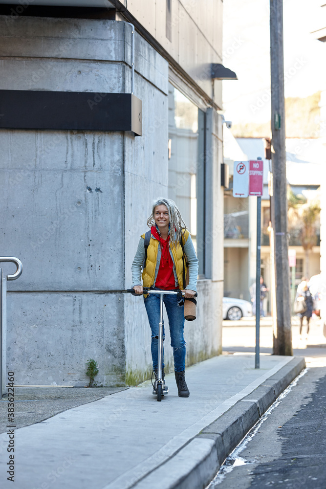 Woman with dreadlocks on electric scooter going to her yoga class Woman with dreadlocks on electric scooter going to her yoga class