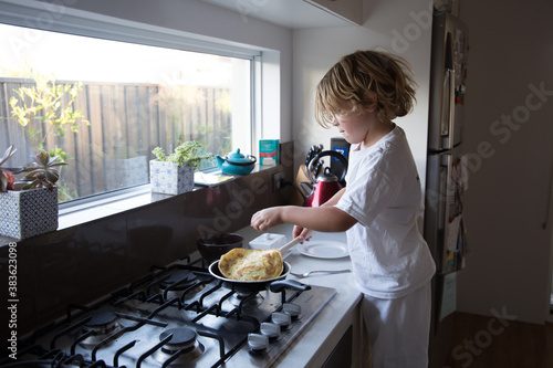 Boy frying omelet for breakfast in kitchen photo