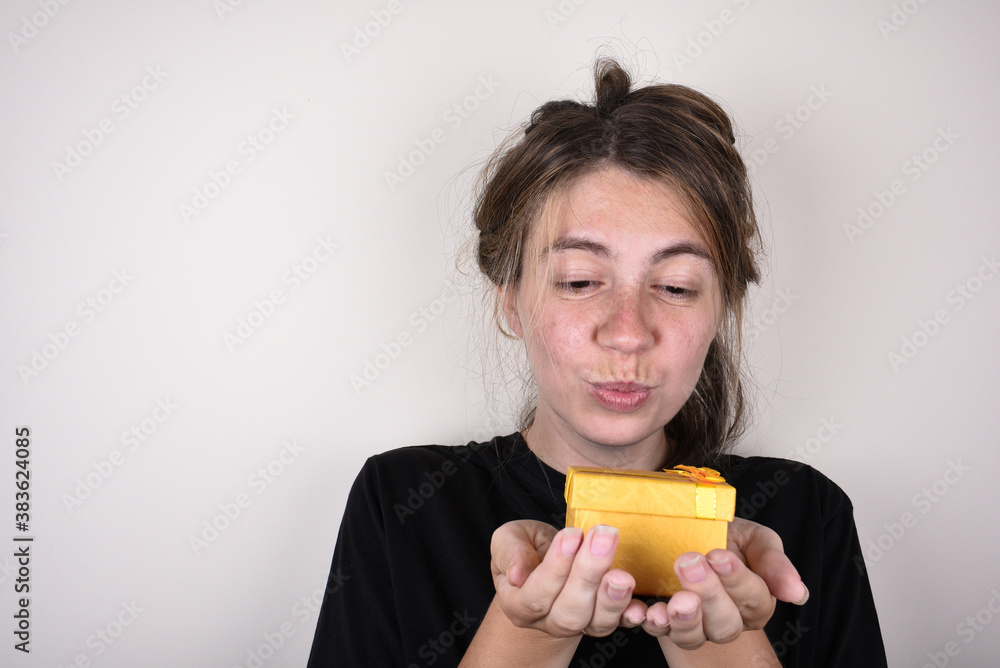 young woman in a black t-shirt on a white background is happy to accepting gift. accept gifts concept young woman in a black t-shirt on a white background is happy to accepting gift. accept gifts concept