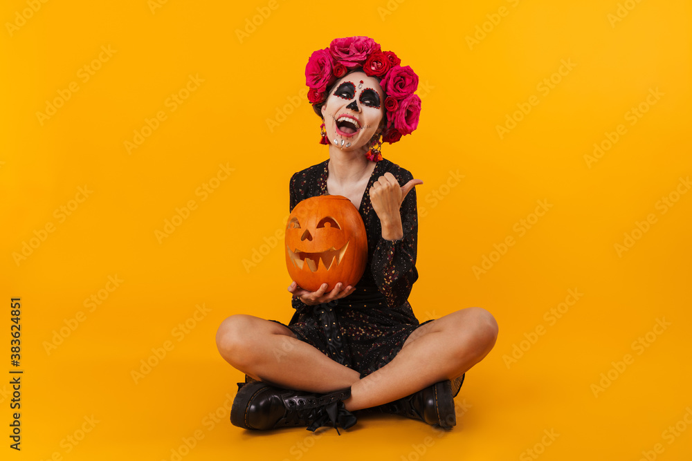 Laughing caucasian girl with pumpkin sitting on floor
