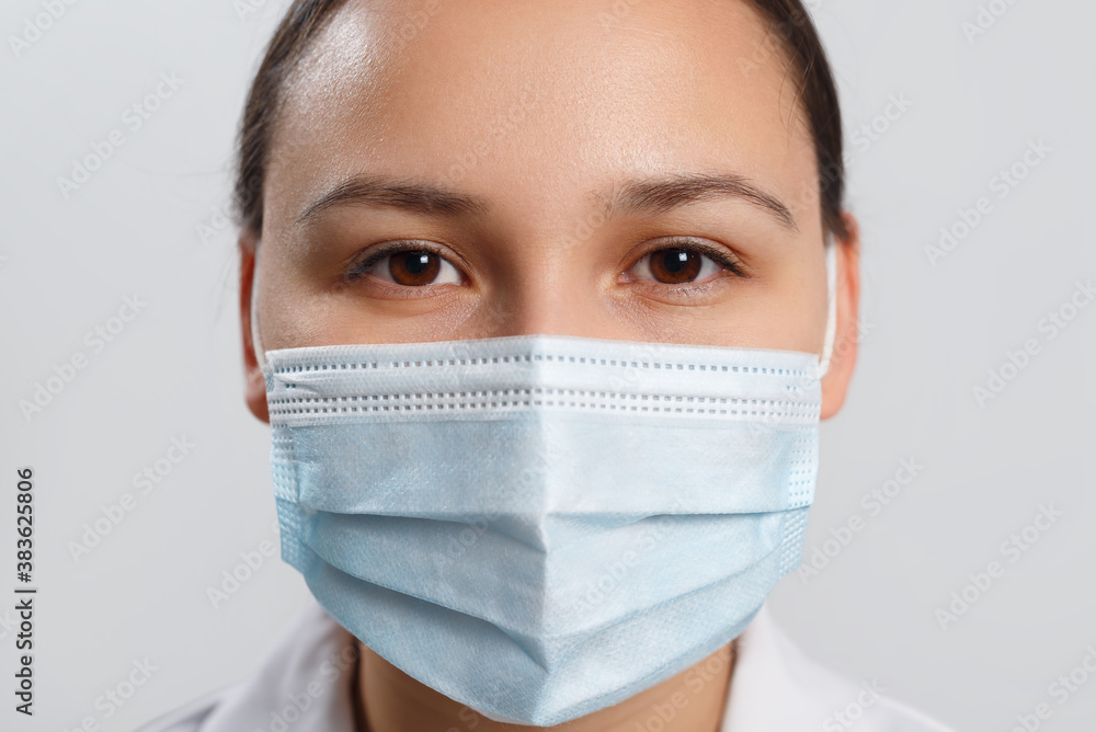 Close-up portrait of a woman covering her face with a medical blue mask, protecting against an outbreak of the coronavirus pandemic infectious disease COVID-19. Close-up portrait of a woman covering her face with a medical blue mask, protecting against an outbreak of the coronavirus pandemic infectious disease COVID-19.