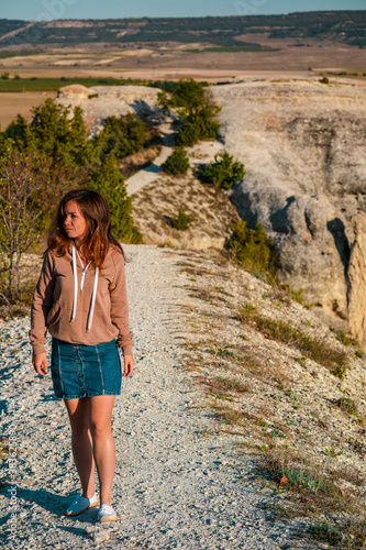 Young woman in jacket walking on narrow path on mountain range © KseniaJoyg