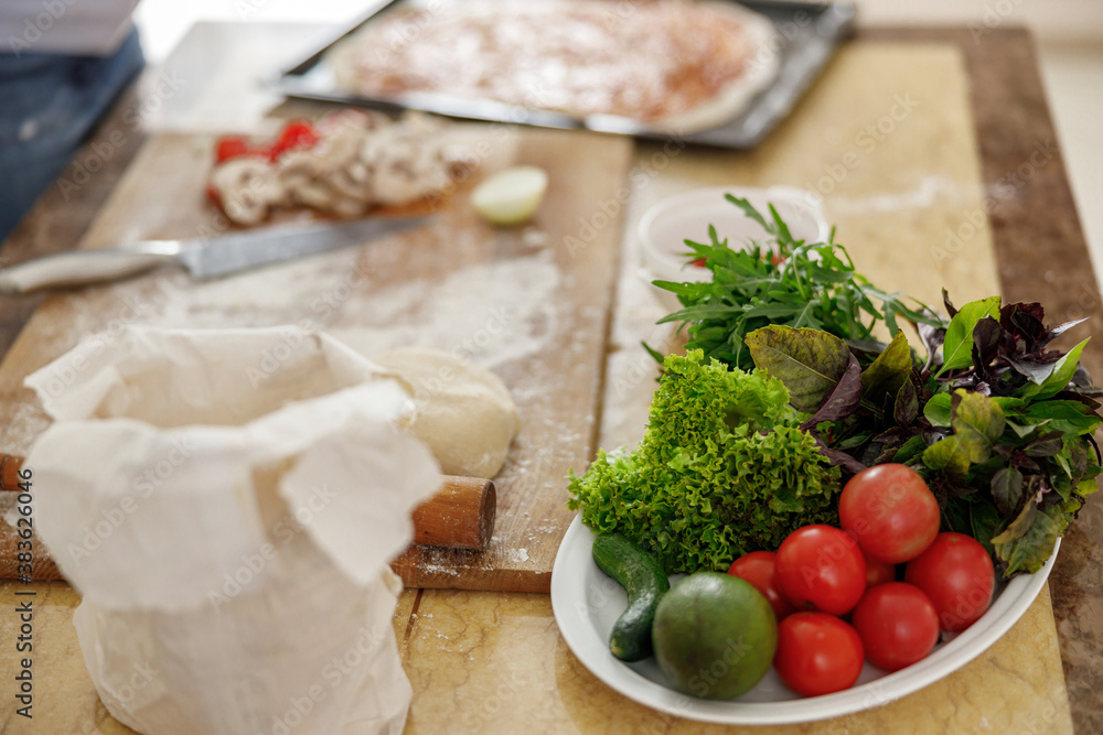 Beautiful smily handsome woman is preparing tasty fresh italian pizzawith vegetables at her kitchen at home Beautiful smily handsome woman is preparing tasty fresh italian pizzawith vegetables at her kitchen at home