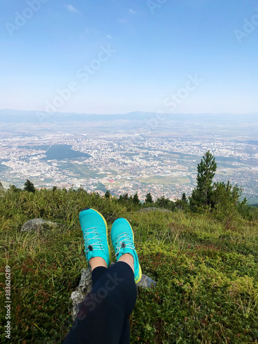 Legs of Woman Traveler Sitting on a High Mountain top with City View.