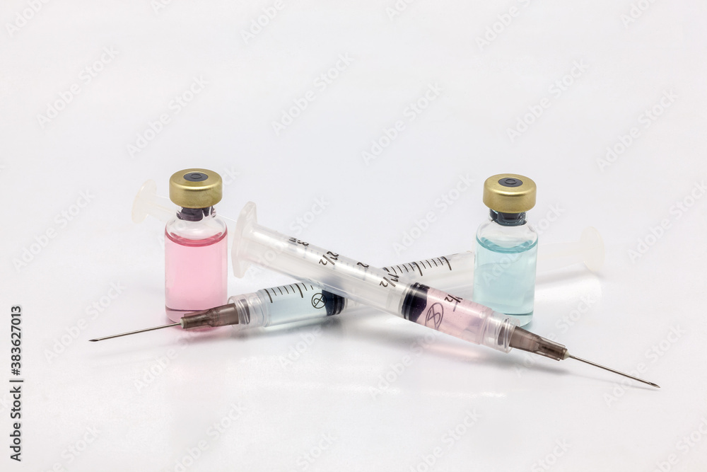 Two different isolated glass vaccine bottles with different colored liquid and two full of colored liquid syringes