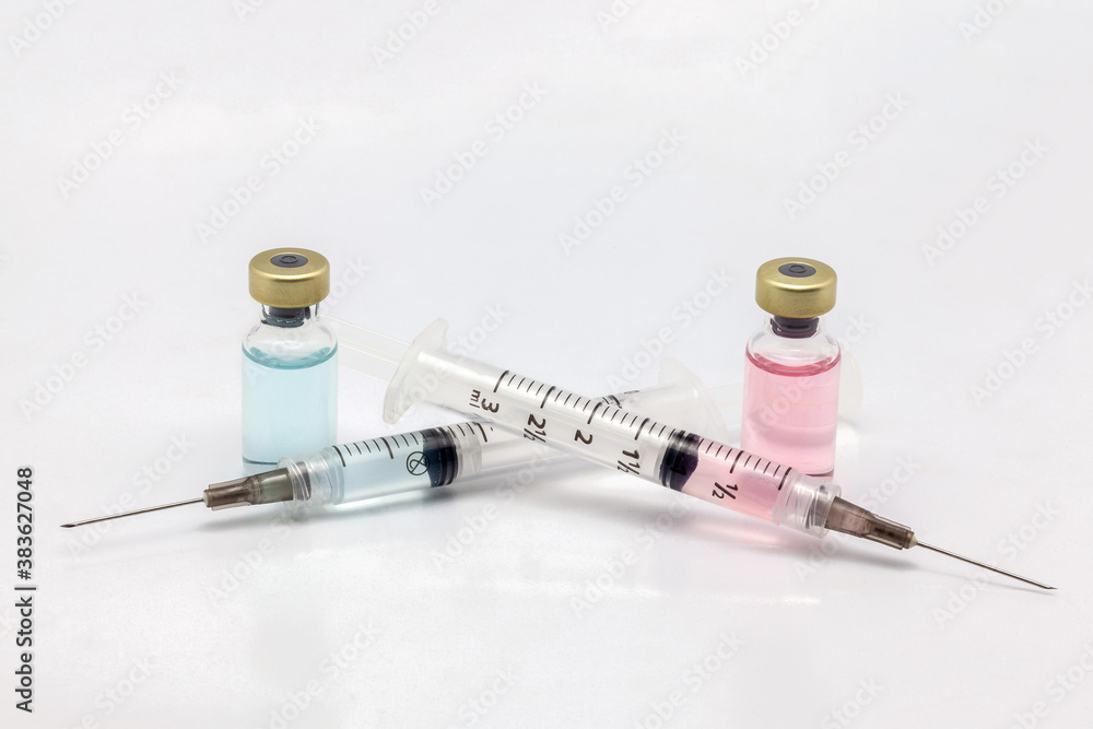 Two different isolated glass vaccine bottles with different colored liquid and two full of colored liquid syringes Two different isolated glass vaccine bottles with different colored liquid and two full of colored liquid syringes
