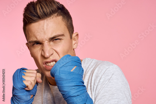 Guy in blue gloves on a pink background are boxing in a white t-shirt cropped view