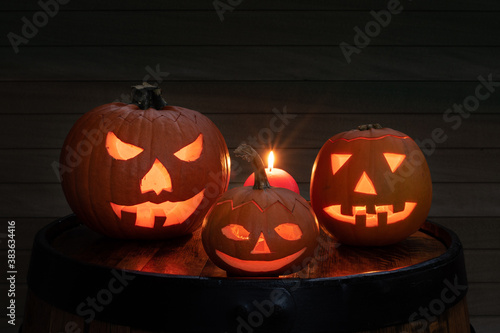 Halloween pumpkin head jack-o-lantern with scary evil faces and candles. Seasonal illuminated decoration.