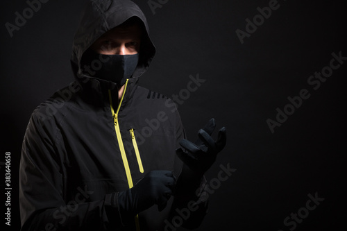 The man in the mask puts on a glove. Preparation for robbery or hacking
