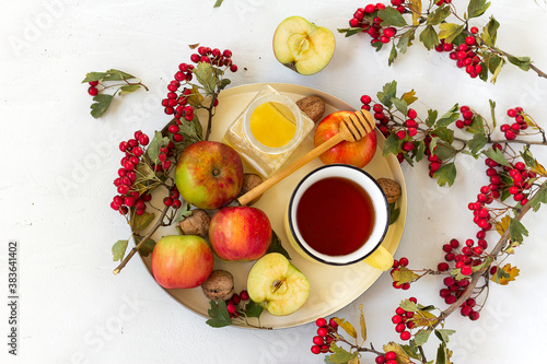 Cozy autumn hot spiced tea with honey, apples and red hawthorn berries on a tray. Still life on white background. Flat lay