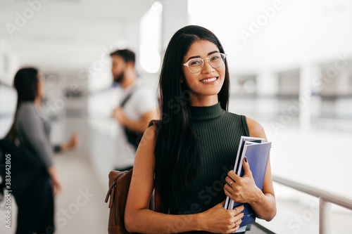 Canvas Print Portrait of young Brazilian student with backpack carrying books in college
