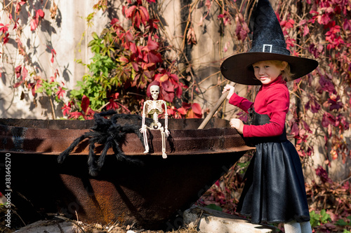 Little girl in a witch costume interferes with a potion on a halloween party
