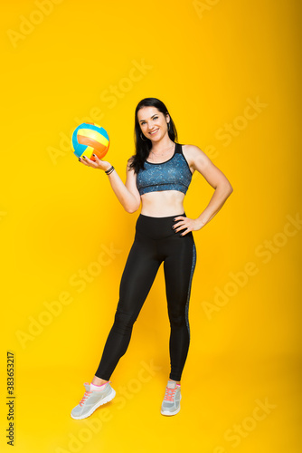 Young beautiful volleyball player isolated on yellow in studio