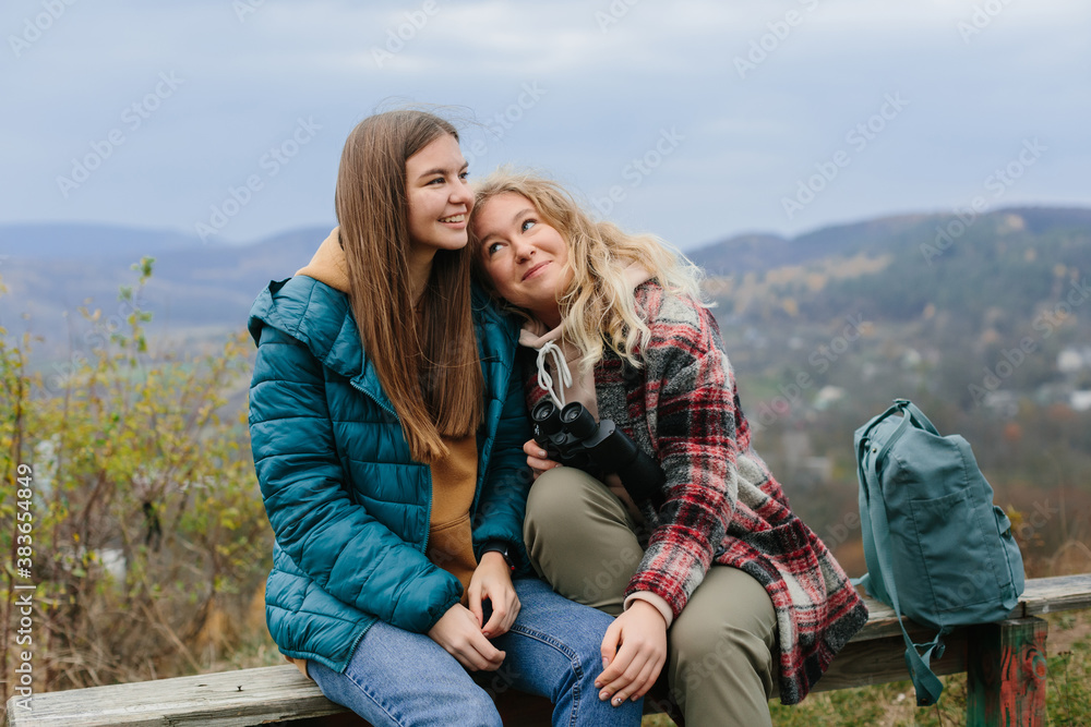 Girlfriends are resting on a bench in the mountains