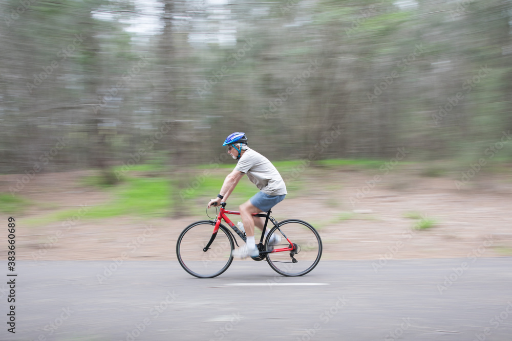 Fototapeta premium Active senior pensioner outdoors active exercising wearing a bike bicycle helmet overcast bit of rain bike path riding a bike keeping busy during self isolation healthy 