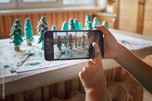 DIY Christmas gifts. Girl making photo of handmade green cones to show friends in social network