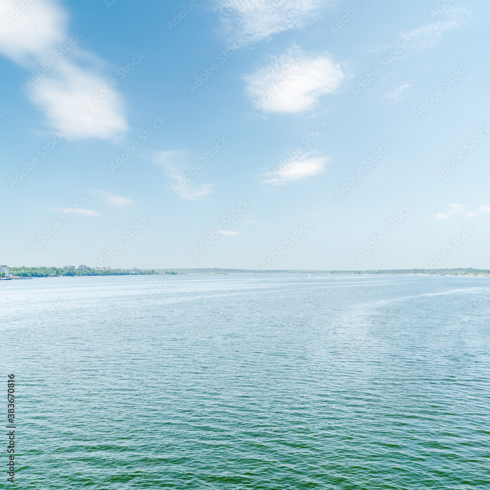 Fototapeta premium blue river and sky with white clouds over it