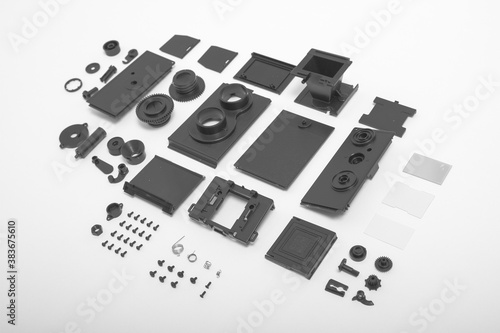 A completely deconstructed knolling style view of a vintage twin-lens camera on white background