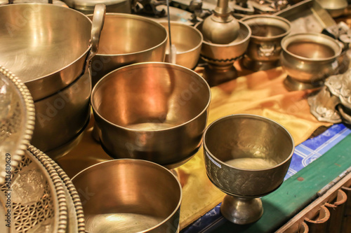 Set of thai traditional brass cookware that include a small and medium-sized saucepan, a large saucepan, pot, and cover stacked on top of the other, and a covered small pot.