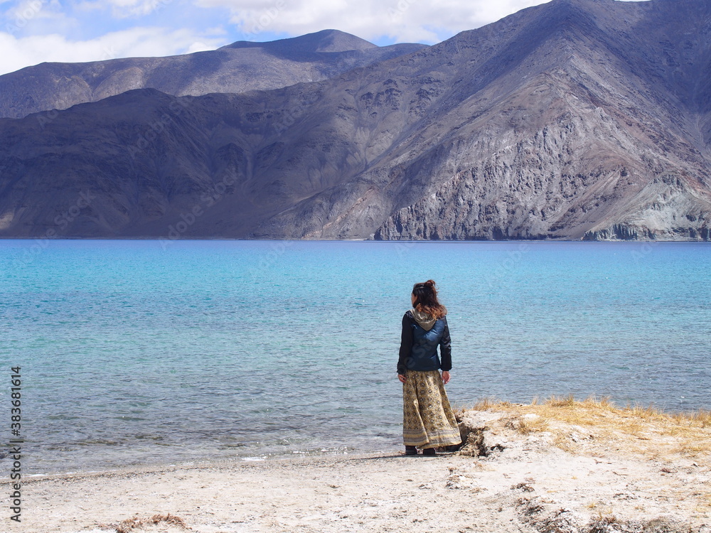 A woman looking out at a beautiful lake, Pangong tso (Lake), Durbuk, Leh, Ladakh, Jammu and Kashmir, India