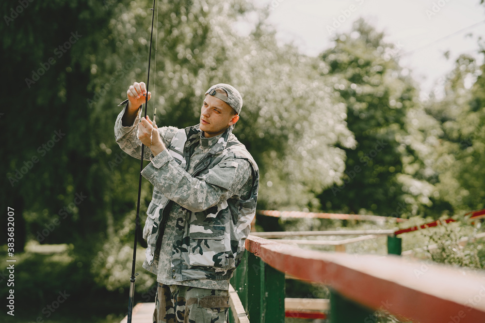Fototapeta premium A man fishing on a lake. Guy in a uniform.