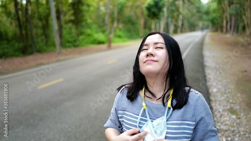 Asia woman portrait taking off the medical mask, breathe deep and smile. End of pandemic. Young pretty girl is happy, quarantine is over. Concept of covid coronavirus infection
