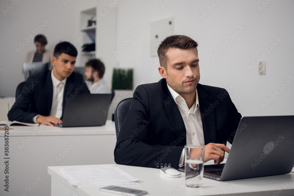 Two managers of a carsharing company are engaged in routine business in the office in a laptop. They are distracted from their work. Two managers of a carsharing company are engaged in routine business in the office in a laptop. They are distracted from their work.