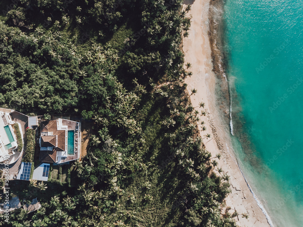 Aerial drone top down view of tropical villa at the paradise beach with pool, palm trees and blue water of Atlantic Ocean, Las Terrenas, Samana, Dominican Republic