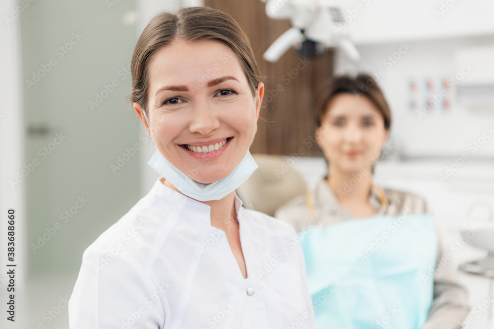 A portrait of a beautiful young doctor with her patient in the back of the picture. A portrait of a beautiful young doctor with her patient in the back of the picture.