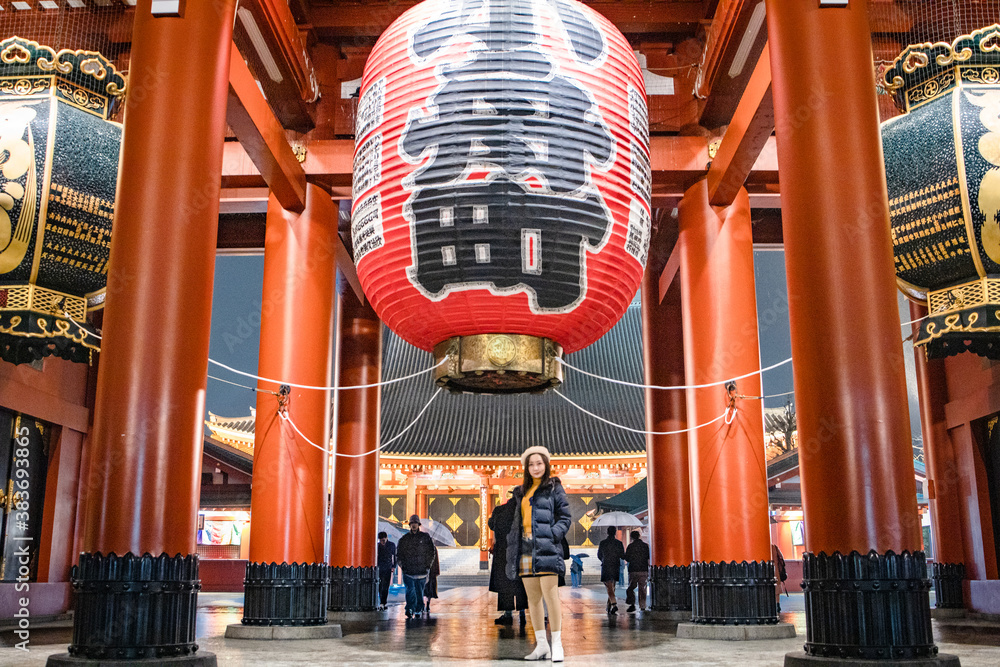 Pretty Girl is standing under Red Lantern of Sensoji Temple’s Kaminarimon gate at main entrance Asakusa, Tokyo, Japan is famous detination for toursit visit at night.