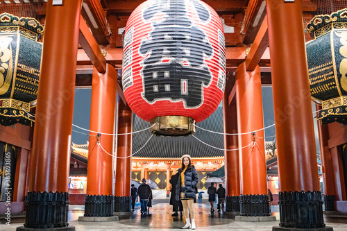 Obraz na płótnie Pretty Girl is standing under Red Lantern of Sensoji Temple’s Kaminarimon gate at main entrance Asakusa, Tokyo, Japan is famous detination for toursit visit at night. w salonie