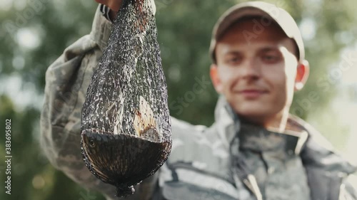 Men's hobby concept. Closeup of a man fisher who caught a fish in an ambush net and looking at it photo