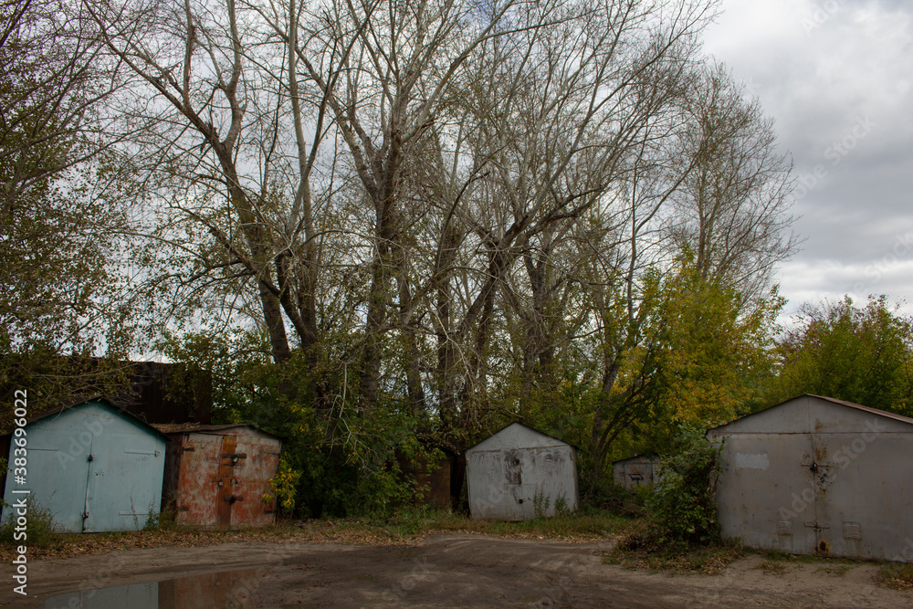 Old metal garages in the corner of the yard. Metal private garages in the corner of the old courtyard under the trees