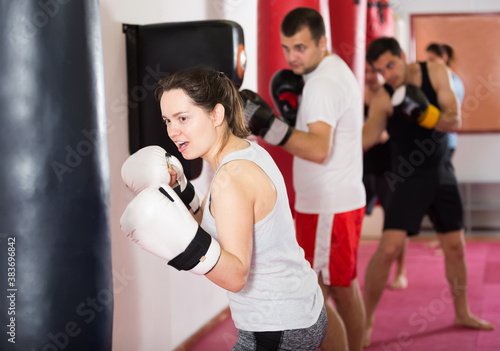 Portrait of girl beating boxing bag training in boxing gloves