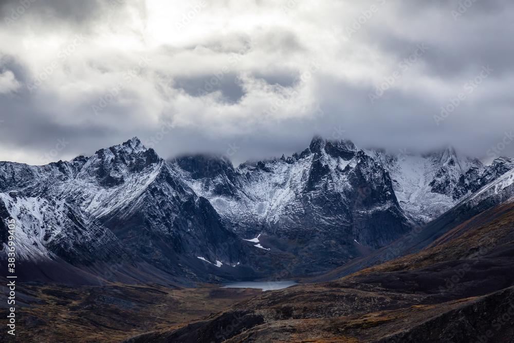 Beautiful View of Scenic Alpine Lake and Snowy Mountains in Canadian Nature. Season change from Fall to Winter. Aerial Shot. Taken near Grizzly Lake in Tombstone Territorial Park, Yukon, Canada. Beautiful View of Scenic Alpine Lake and Snowy Mountains in Canadian Nature. Season change from Fall to Winter. Aerial Shot. Taken near Grizzly Lake in Tombstone Territorial Park, Yukon, Canada.