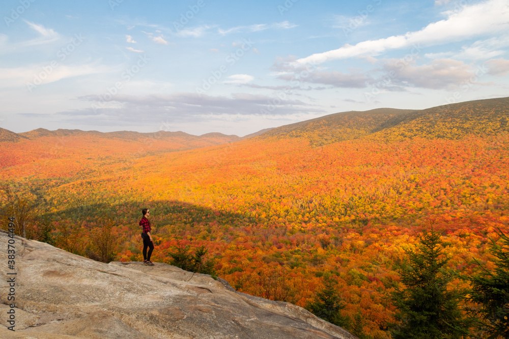 Young woman standing on a cliff and admiring the autumnal colors in the Mont-Megantic national park, Canada Young woman standing on a cliff and admiring the autumnal colors in the Mont-Megantic national park, Canada