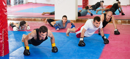 Portrait of young diligent females and adult males training in boxing gloves