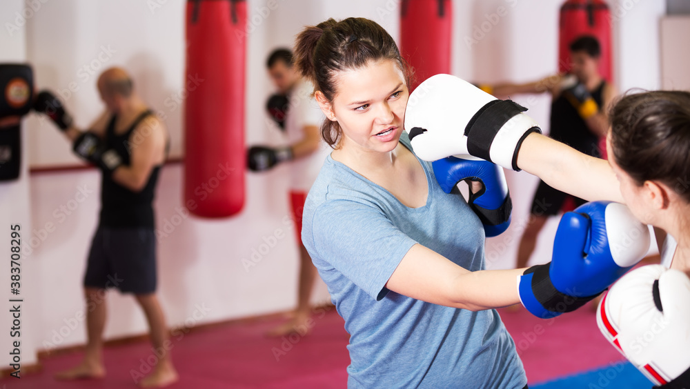 Two young athlete girls practicing boxing sparring in gym