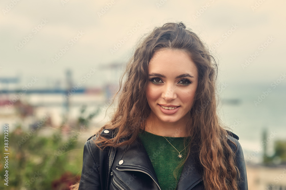 Portrait of a young beautiful girl in a leather jacket in the city