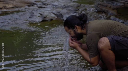 vivek bearded long hair man washing face in fresh water in jungle water . photo